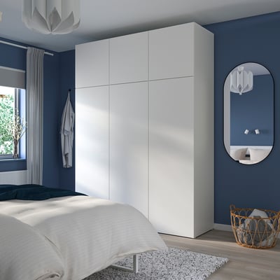 A modern blue bedroom with a large white PLATSA wardrobe reaching the ceiling.
