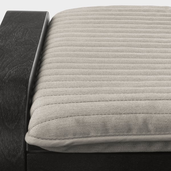 Close-up a POÄNG cushion with smooth, textured fabric and neat stitching on a black armchair.