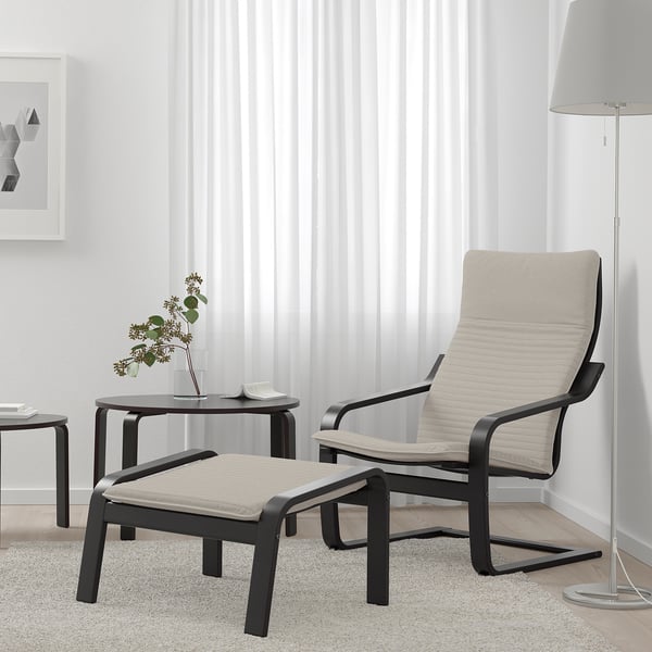 Minimalist living room with POÄNG beige chair & ottoman, black coffee table, lamp. Simple decor.
