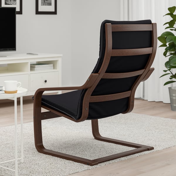 A black cushioned armchair with wooden frame and curved back sits on a rug in a living room.