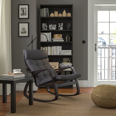 Modern living room with POÄNG rocking chair, bookshelf, teacup & ottoman.