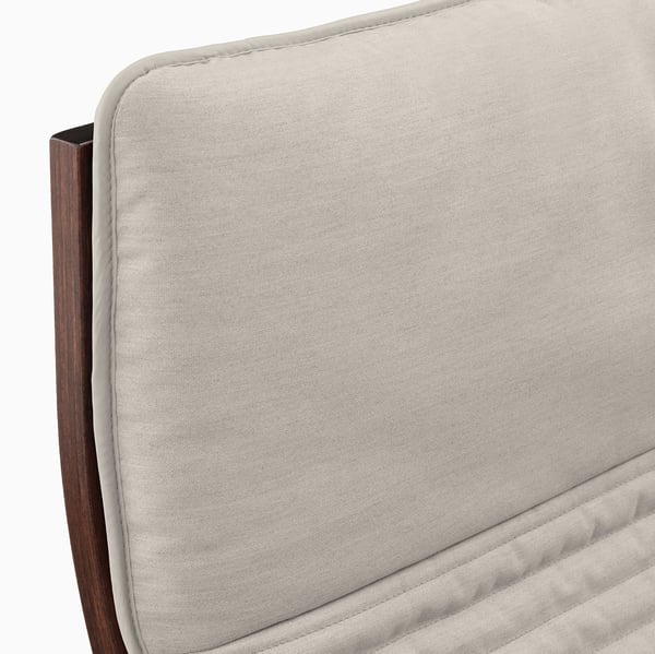 POÄNG armchair close-up: plush, cream-colored cushion meets sleek, dark wooden frame, showcasing quality craftsmanship.
