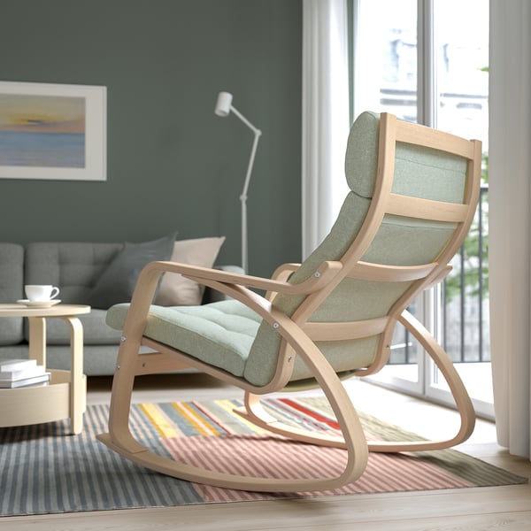 Sleek, light wood rocking chair with green cushion near window, comfortable for relaxation.