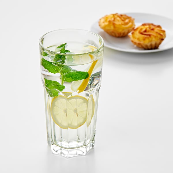 A tall glass of water with lemon and mint, placed beside a plate with two pastries. Refreshing, clear, and inviting.