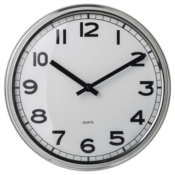 A round, white clock named PUGG with black numbers and hands, a silent quartz movement, and a stainless steel frame.