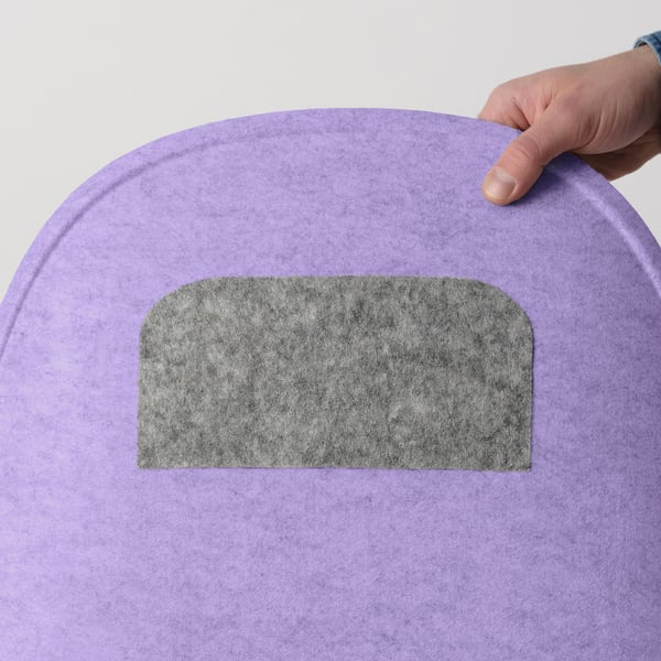 Hand placing a grey seat pad on a purple chair, showing its non-slip function.