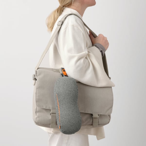 Person carrying RAGGARV memory foam neck-lumbar pillow with adjustable straps, designed for comfort and ergonomic seating.