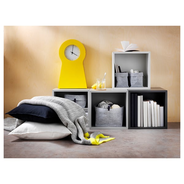 A bright living space a yellow clock, cushions, and modular units with RAGGISAR grey felt baskets storing various items.