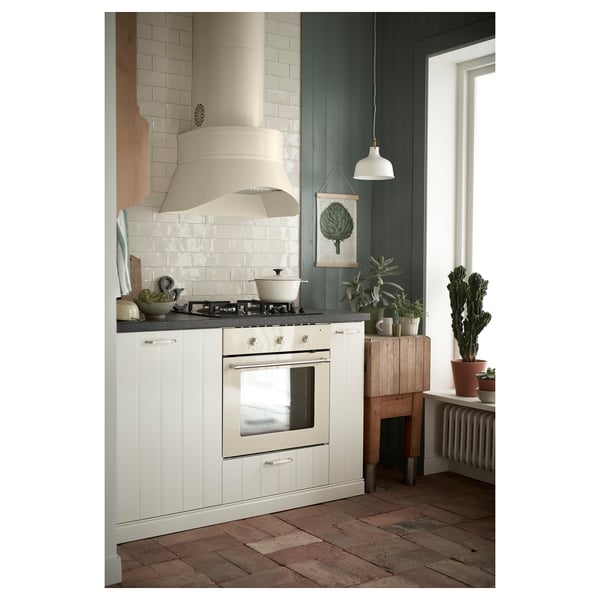 Cosy kitchen: white cabinets, silver stove, black countertop with plants, green art, grey radiator.