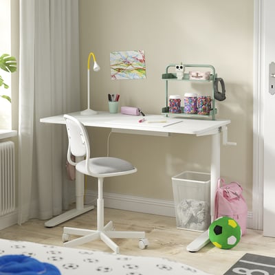 A childs white adjustable desk setup with a grey chair, colourful accessories, and a green shelf.