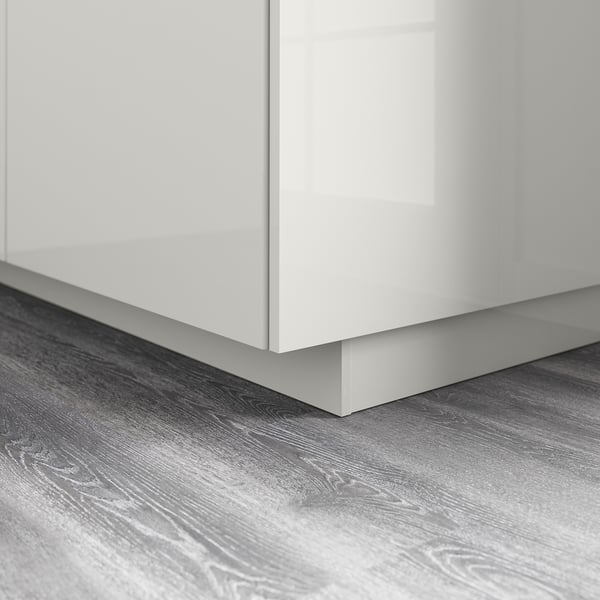 White glossy kitchen cabinet base with grey wood-patterned floor.