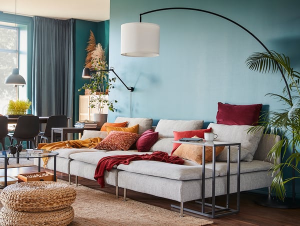 Cosy living room with blue walls, grey lamp, pendant light, grey sofa, plants.