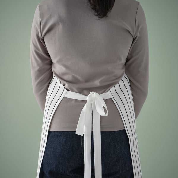 Apron tied around persons waist, with water-repellent surface for easy cleaning, adjustable neck-band fits all sizes.