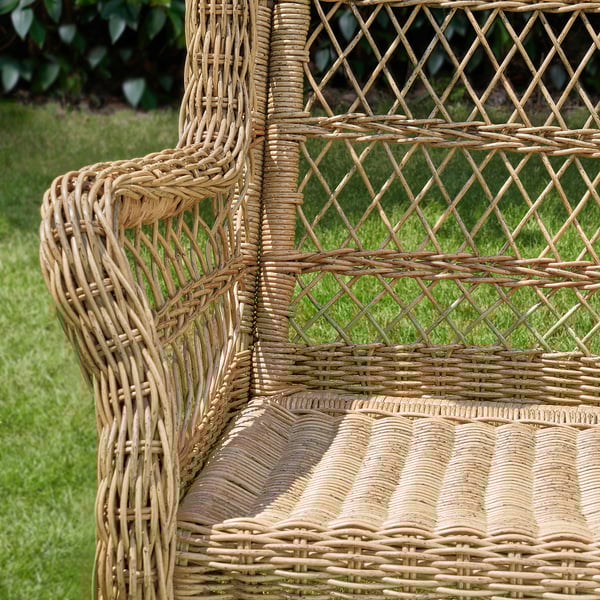 Wicker outdoor chair with intricate weaving, designed for comfort. Natural tones blend with greenery.