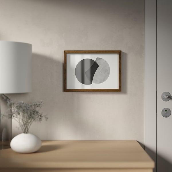 A modern frame hangs on a wall, showcasing an abstract picture with grey shades, positioned beside a closed door with a doorknob.