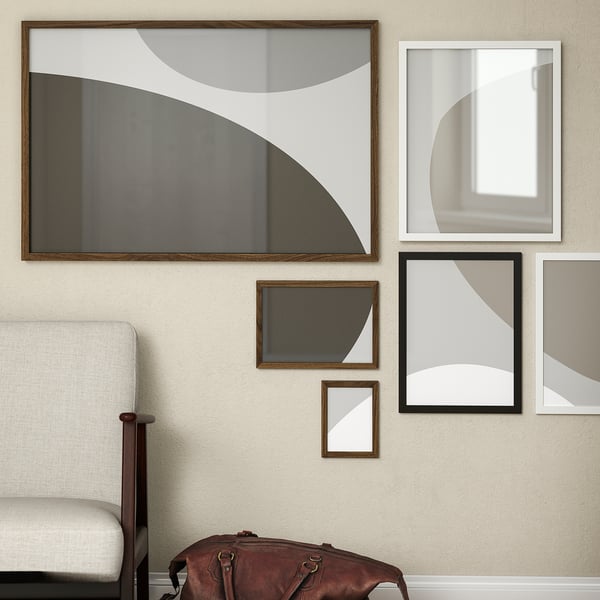 Modern wall art with RÖDALM frames, varying sizes and patterns. White chair and brown bag below.