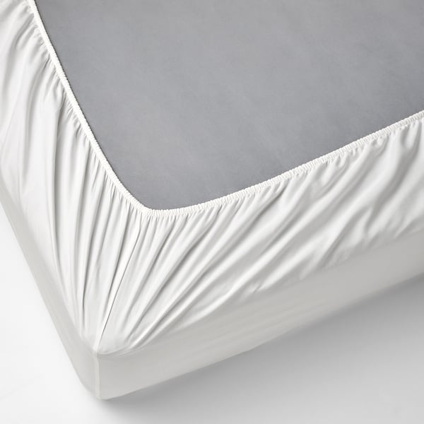 White bed sheet with elastic edges on a grey mattress, demonstrating how it fits snugly and stays neat.
