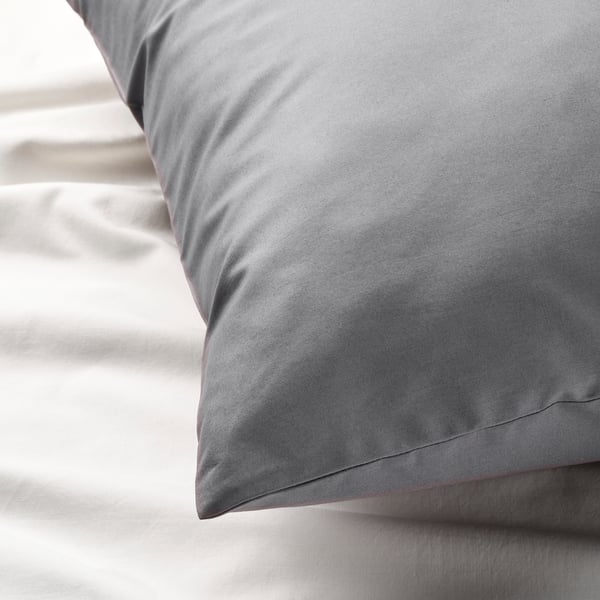Close-up of smooth, high-quality grey cotton pillowcase on bed.