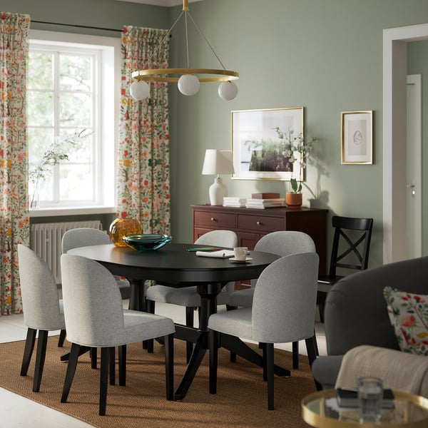 Modern dining room with ROSENTORP grey chairs, black table, floral curtains, green walls, and hanging light. Chairs upholstered in recycled polyester.