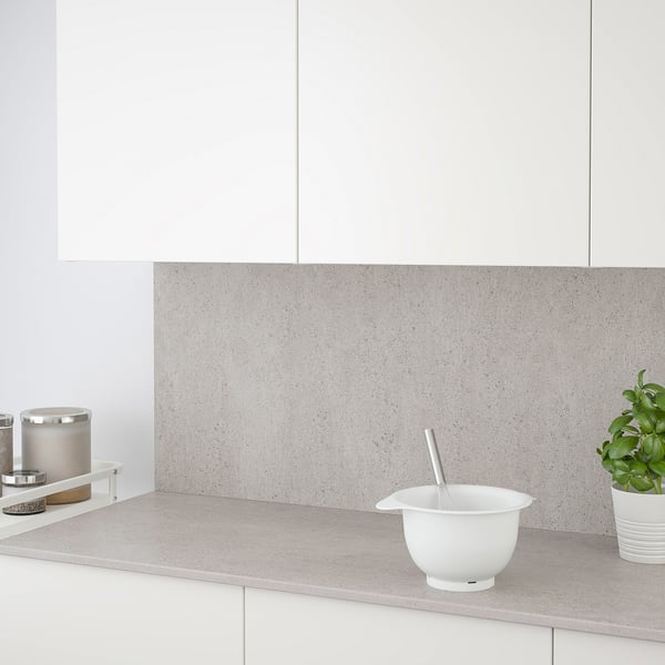 Modern kitchen with porcelain countertop, backsplash, bowl, spoon, candle holder, and plant. Easy-to-clean and grease-resistant.