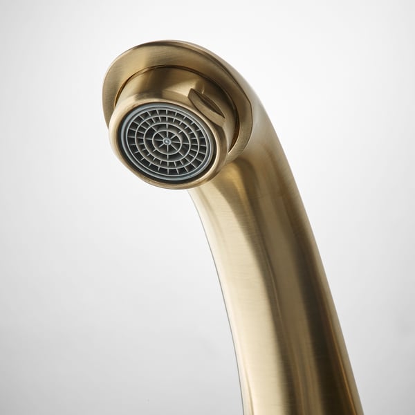 Golden tap close-up showcasing a sleek, curved design with a built-in water-saving aerator at the tip.
