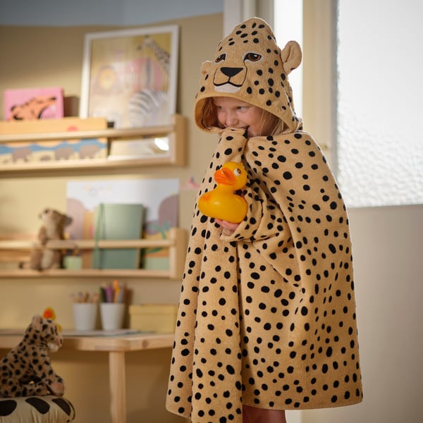 Child in cheetah print towel with duck, near toys.