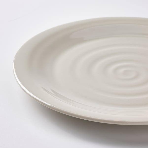 Close-up: smooth white plate with rippled edge, earthy texture.