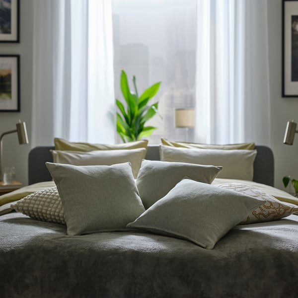 Bed with green cushions, plant, lamp.