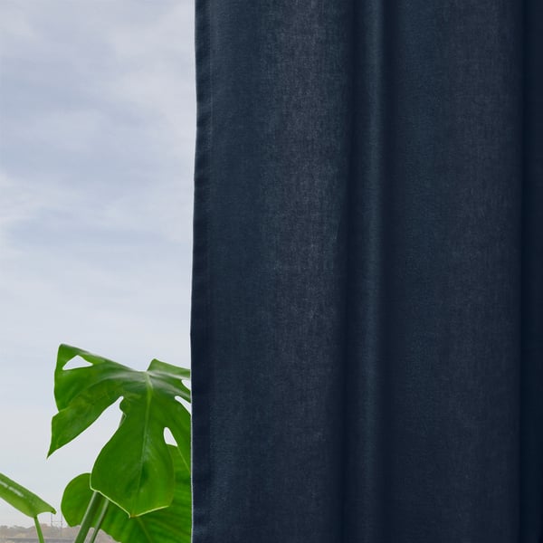 Dark blue velvet curtains hang by a window, filtering soft light. A green plant stands by, contrasting with the room-darkening fabric.