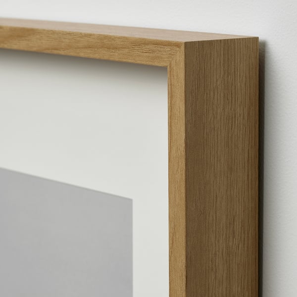 Close-up of a wooden picture frame corner. Light brown, high-quality wood grain texture visible.