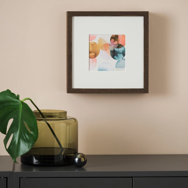 Abstract painting on wall above black cabinet with green plant in yellow vase. Frame has deep front protection.