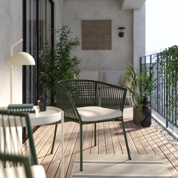 Balcony scene with SEGERÖN green chair, white cushion, lamp, plants, and wooden floor.