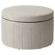 Round grey fabric storage ottoman with pleated sides and decorative piping.