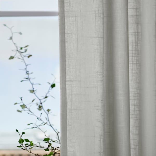 Grey SILVERLÖNN curtains philtre light by window, plant in foreground.