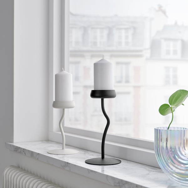 Window ledge with modern black and white candlesticks, marble surface, small plant in colourful vase.