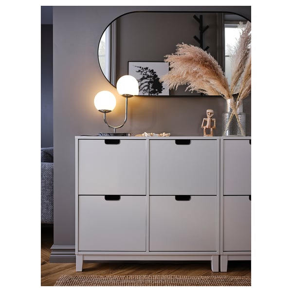 Modern living space featuring a light grey SIMRISHAMN lamp on a stylish cabinet, decorated with a vase and ornamental plants.