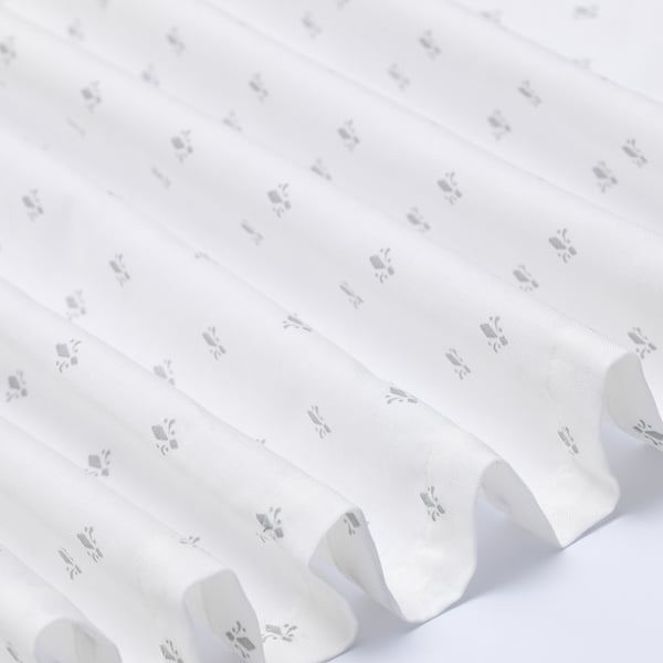 Elegant white curtains with subtle grey floral patterns neatly arranged, showcasing quality fabric and design.