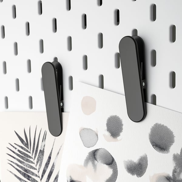 Black SKÅDIS clips hold papers on a pegboard.
