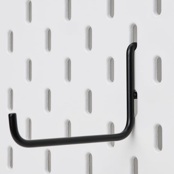 Black SKÅDIS hook securely mounted on a white pegboard, ideal for organising items.