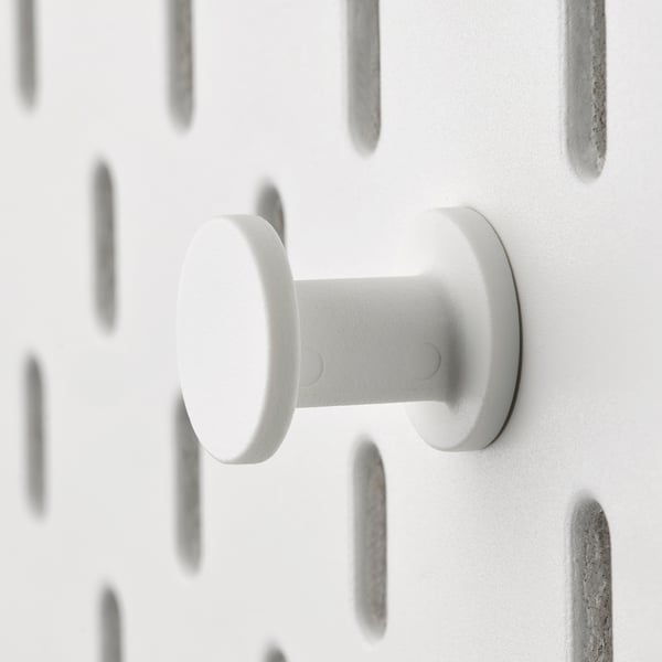 White plastic hook on pegboard, circular base, stable design.