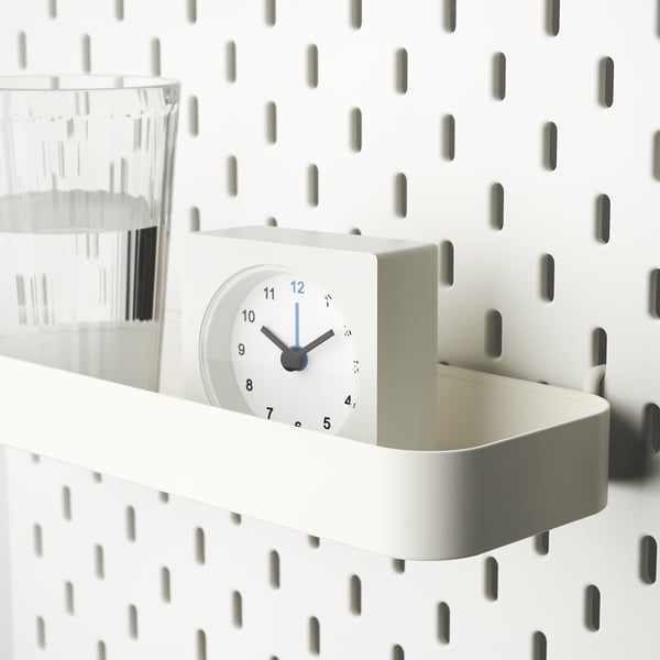 White SKÅDIS shelf with clock and glass. Keeps items organised and time displayed.