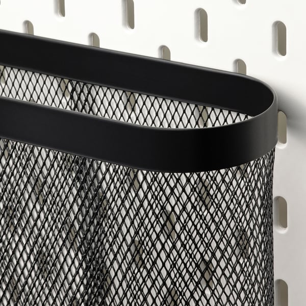 Black metal mesh organiser with rounded top attached to a wall with hooks. Sturdy and stylish storage solution.