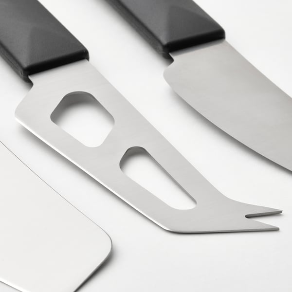 Three stainless steel cheese knives with black handles, positioned closely together, showcasing their sharp edges and functional design.