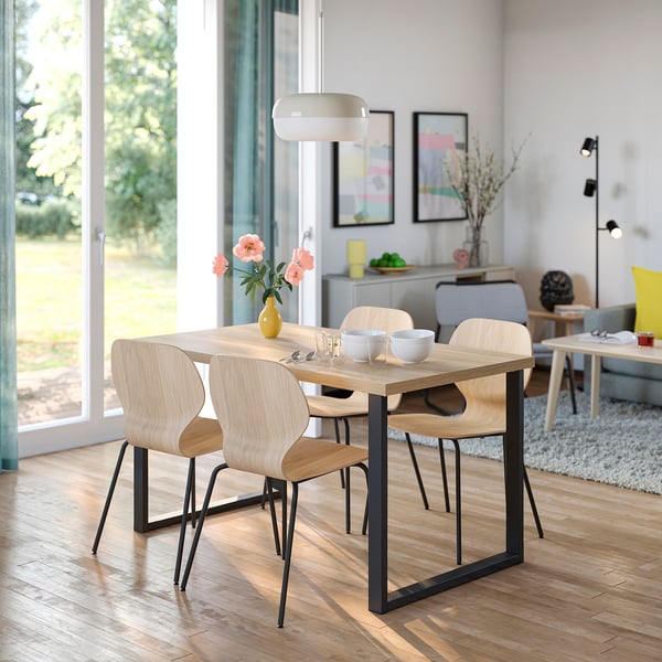 Modern wood dining set with black metal legs. Four chairs, light wood tops, white flowers.