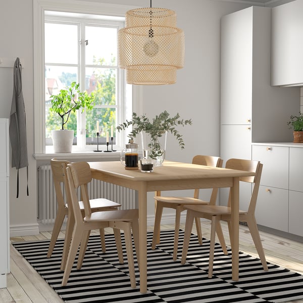 Bright dining area with SKANSNÄS 4-seat extendable table, chairs, and pendant light on a rug near a window with greenery.