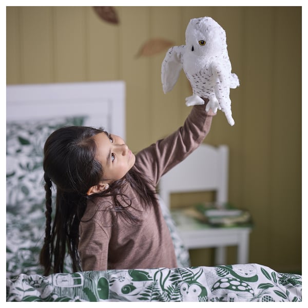 Child holds soft owl puppet in cosy room