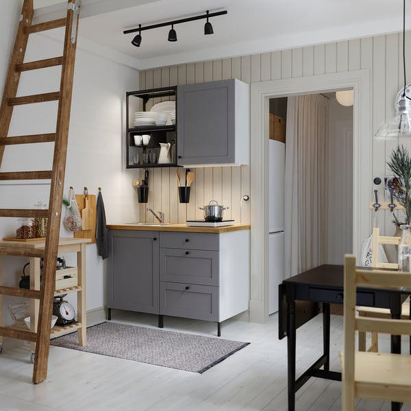Modern kitchen with grey SKURUP lamps over counter, wooden ladder, and dining area.