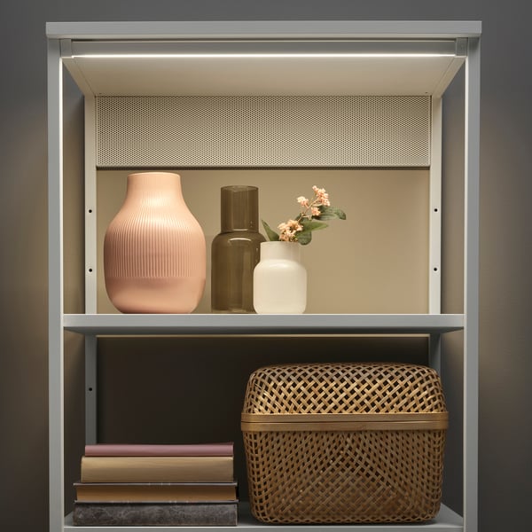 Modern bookshelf with led lights, displaying vases and basket.