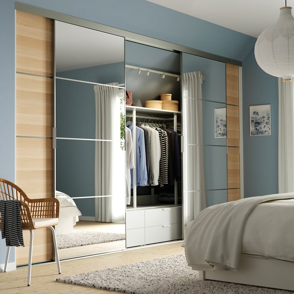 Modern bedroom with blue SKYTTA closet, wooden panels, and minimalist decor.