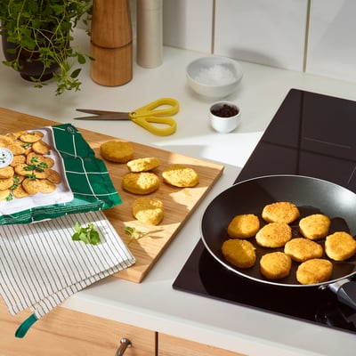 Open bag of SLAGVERK wheat-based pieces on a kitchen counter. Breaded pieces on a board and in a pan, frozen pieces visible in the bag.